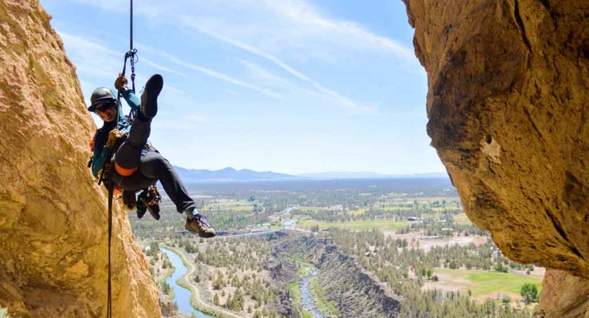 a person poses for a photo midair while rappelling 